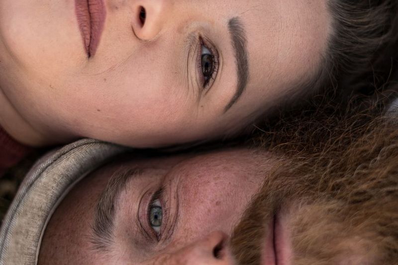 A close-up of a couple lying together, expressing love and relaxation in an outdoor setting.