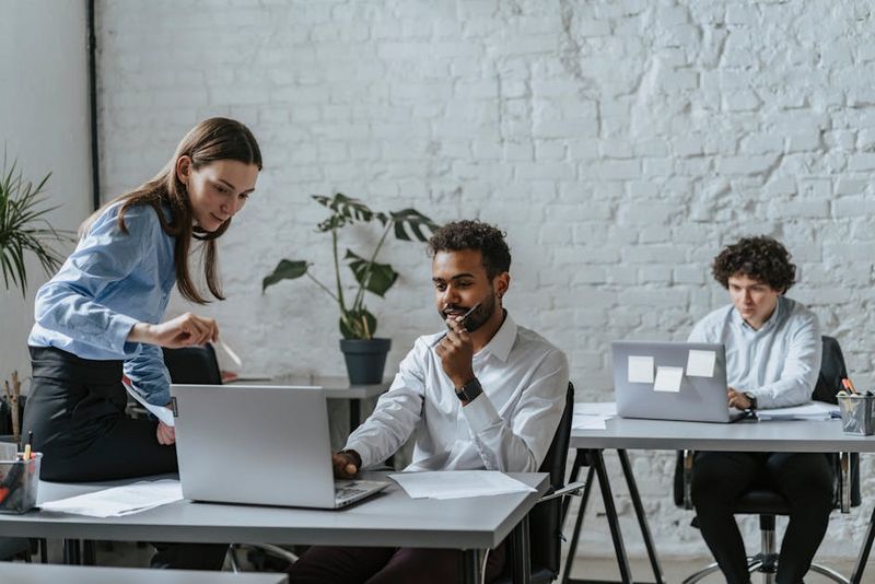 A group of professionals collaborating in a modern office setting, engaging with technology and teamwork.