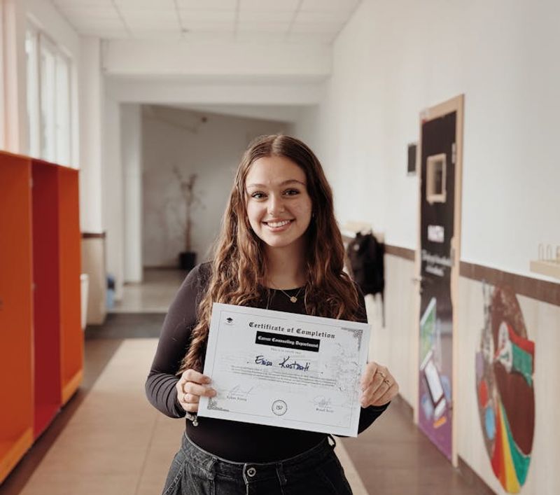 Smiling woman proudly displays certificate in a school corridor. Achievement and success captured.
