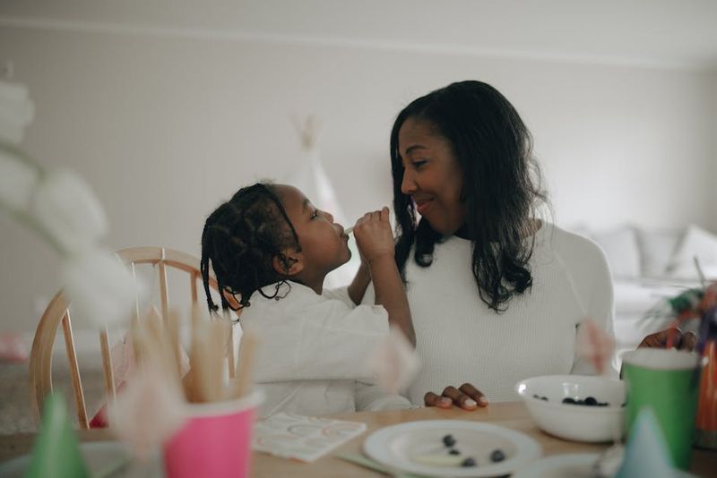African mother and daughter smiling and bonding over breakfast at home.
