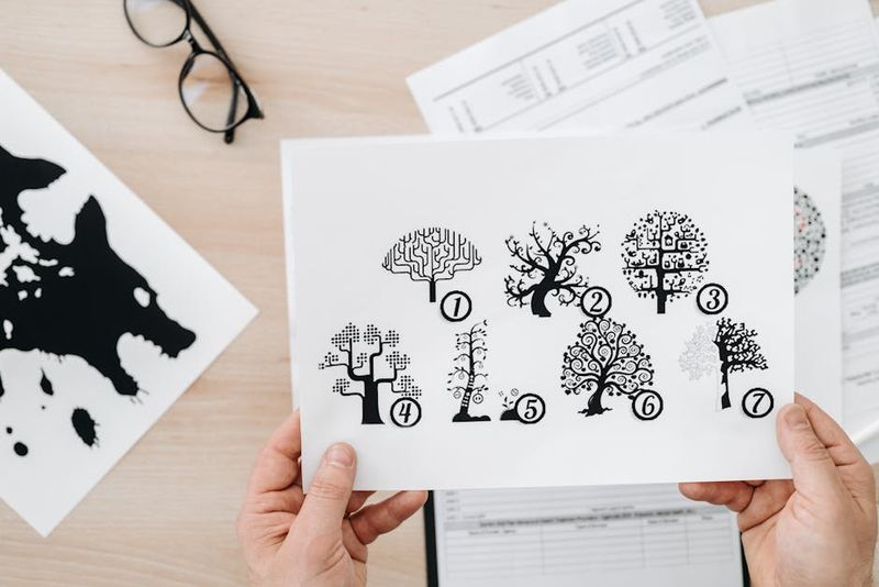 Nahaufnahme von Händen, die Papier mit einer Baumtest-Illustration für eine psychologische Beurteilung halten.