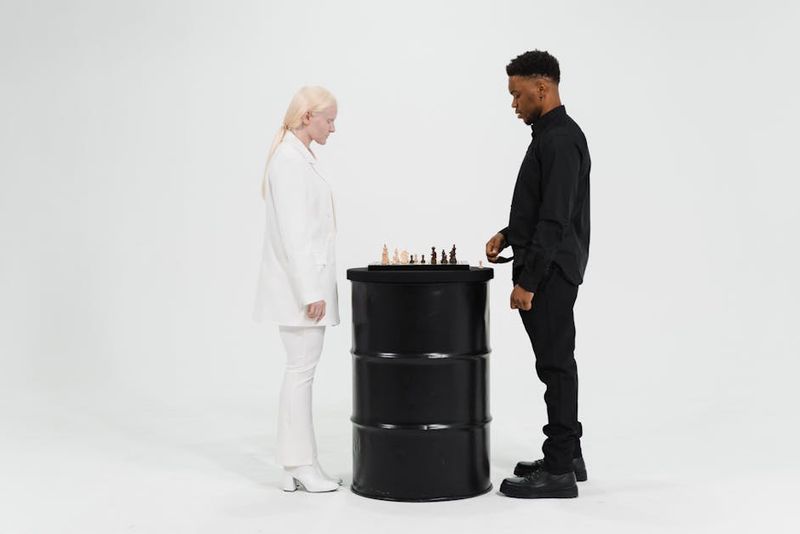 Zwei Personen vertieft in eine Schachpartie, die Strategie auf einem minimalistischen Aufbau demonstriert.
