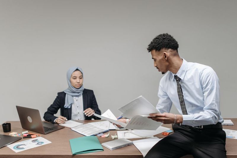 Muslim business professionals collaborating at desk in modern office.