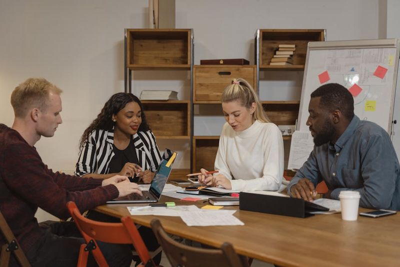 Un team multiculturale in un ufficio moderno impegnato in una riunione collaborativa, che discute le strategie del progetto.
