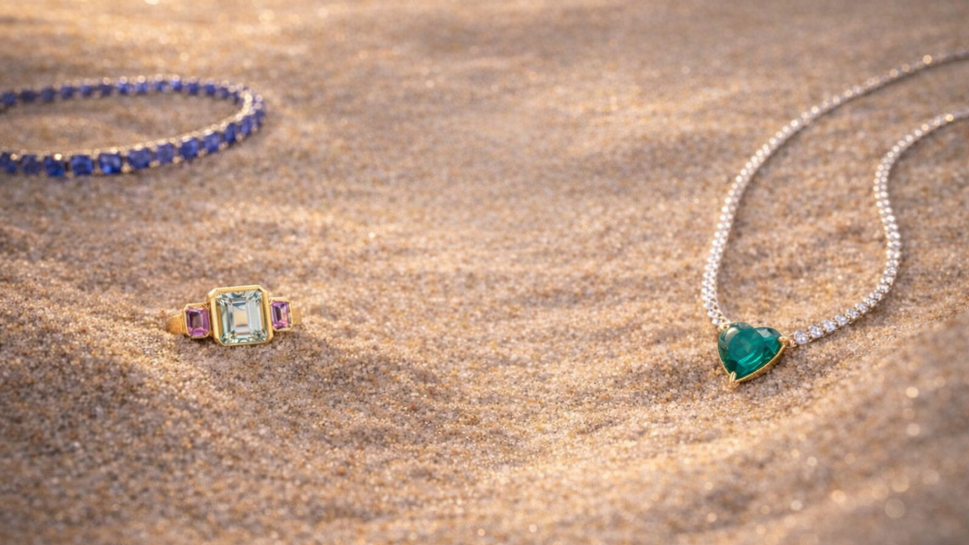 SAPPHIRE BRACELET, AQUAMARINE AND MORGANITE RING, HEART SHAPED EMERALD AND DIAMOND NECKLACE IN THE SAND