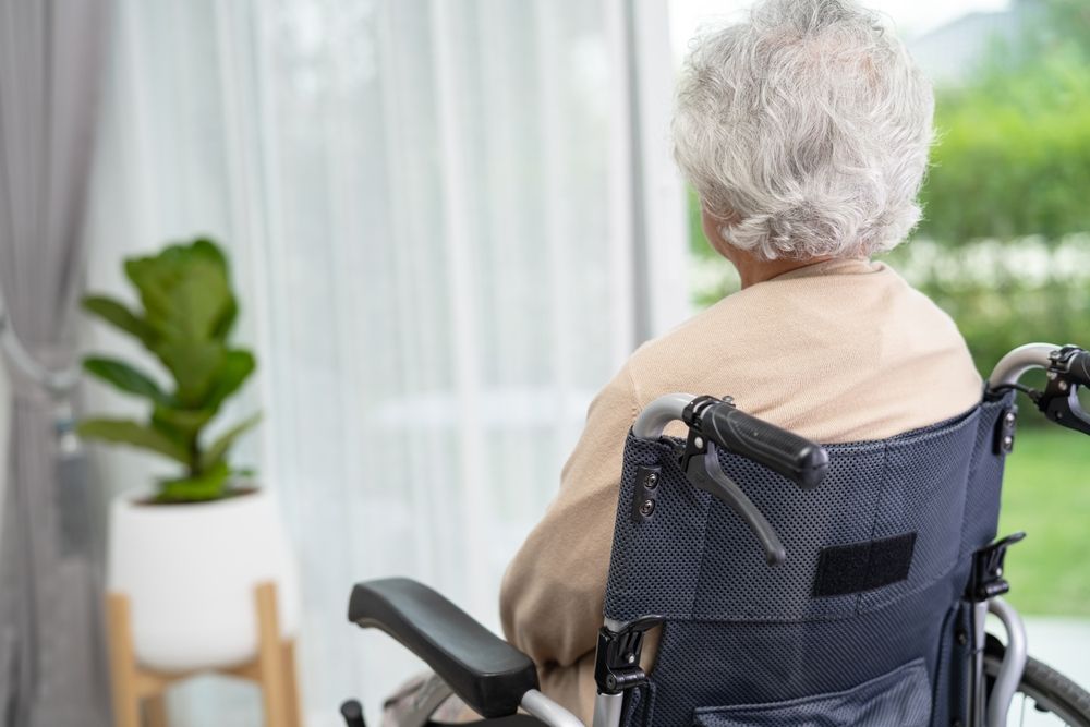Elderly nursing home resident sitting in a wheelchair near a window, representing possible nursing home neglect warning signs in South Jersey.