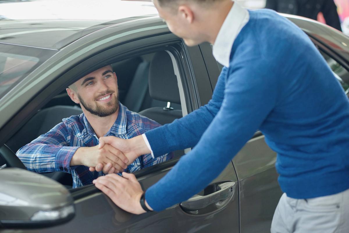 young-man-blue-sweater-helping-friend-choosing-vehicle