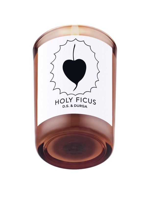 A lit scented candle with a label reading "holy ficus" d.s. &amp; durga on a transparent background.