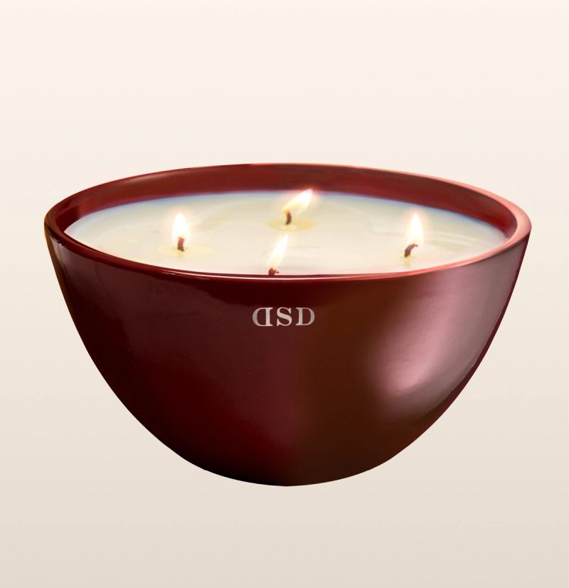 A multi-wick scented candle in a maroon bowl with a glossy finish.