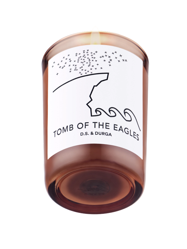 A lit scented candle named "tomb of the eagles" by d.s. &amp; durga, depicted against a transparent background.