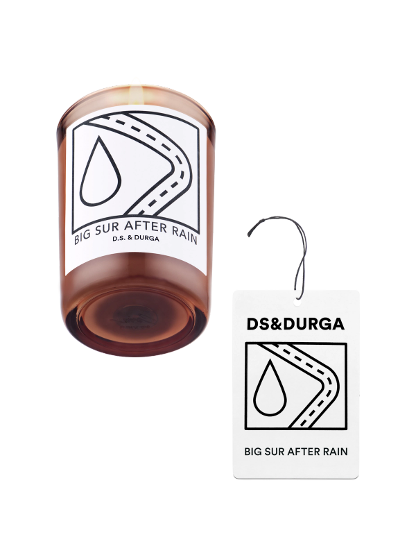 An elegant, lit scented candle by d.s. & durga with big sur after rain fragrance, accompanied by a matching auto fragrance.