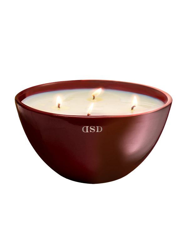 A multi-wick scented candle in a maroon bowl with a glossy finish.