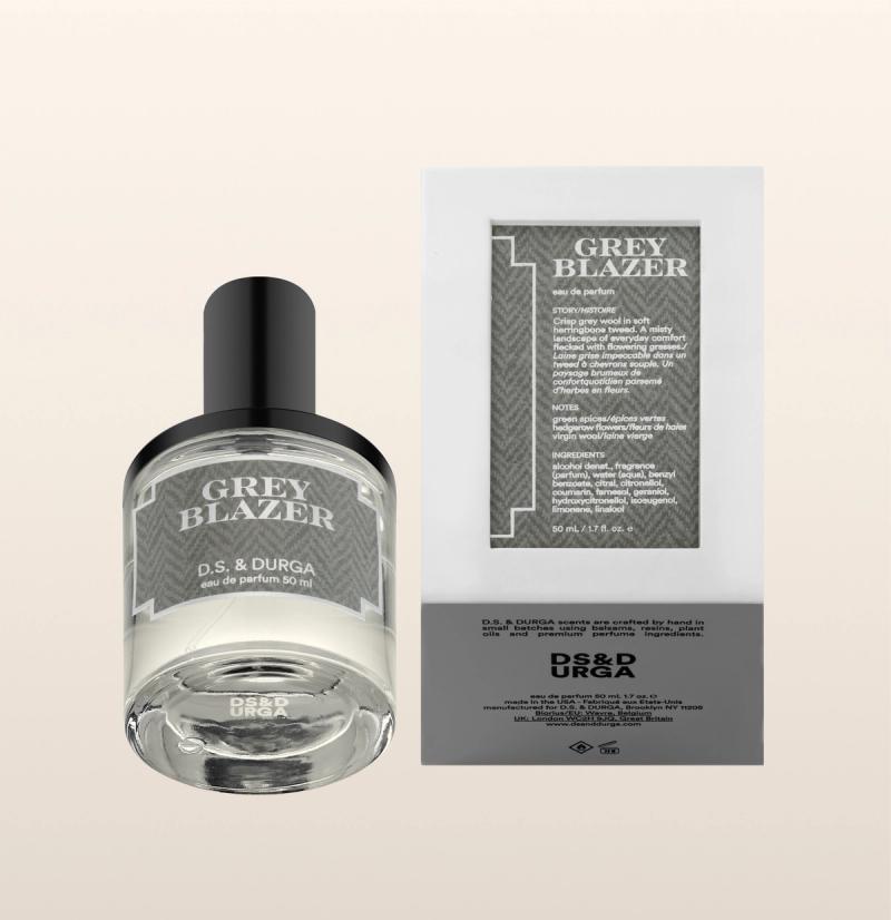 A bottle of D.S. & Durga Grey Blazer eau de parfum sits next to its packaging, which displays product details and branding in grey and white on a neutral background.
