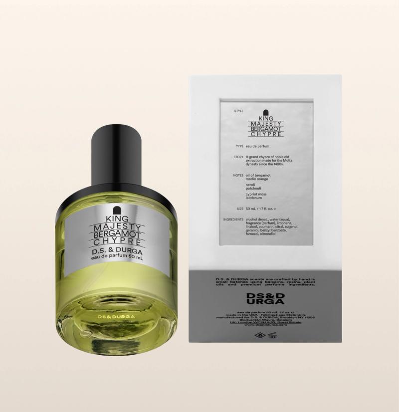 A perfume bottle labeled "King Majesty Bergamot Chypre" by D.S. & Durga is next to its box. The bottle contains a yellow liquid and has a black cap. The box is white with detailed text about the fragrance.