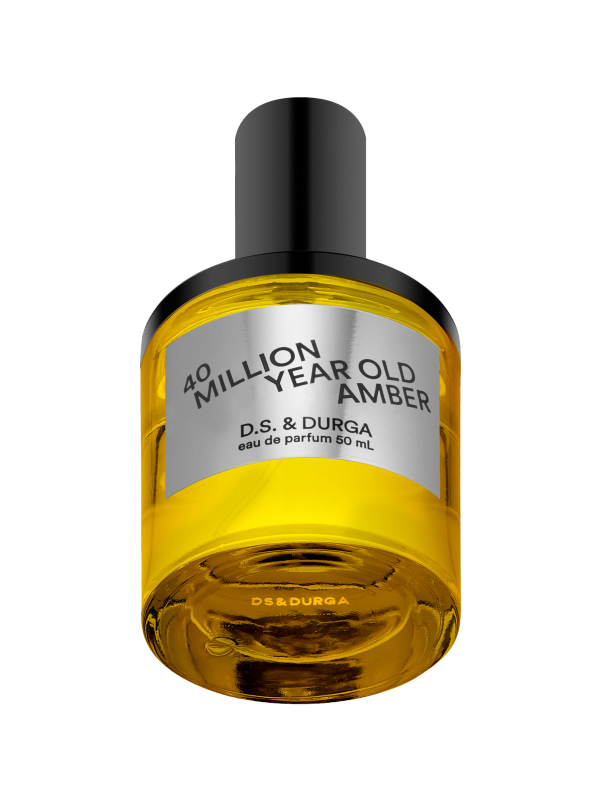 A sleek bottle of "40 million year old amber" eau de parfum by d.s. &amp; durga, 50 ml, showcasing golden amber-colored liquid with a reflective metallic label and a black cap.