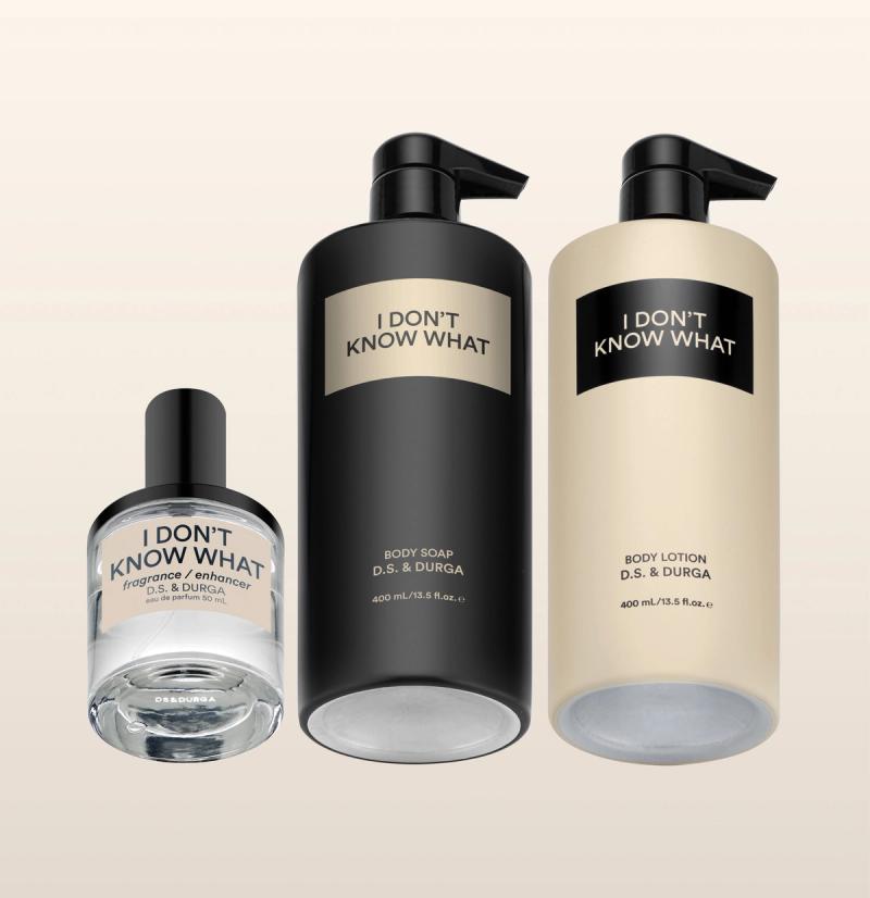 Three bottles of personal care products with minimalist design labeled "I Don't Know What" including a clear bottle of fragrance, a black bottle of body soap, and a beige bottle of body lotion on a neutral background.