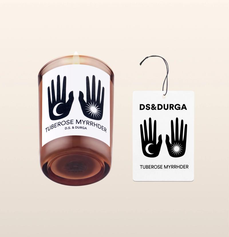 An elegant, lit scented candle by d.s. & durga with tuberose myrrhder fragrance, accompanied by a matching auto fragrance.