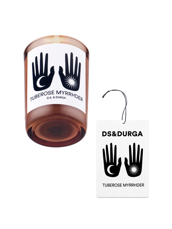 An elegant, lit scented candle by d.s. & durga with tuberose myrrhder fragrance, accompanied by a matching auto fragrance. 