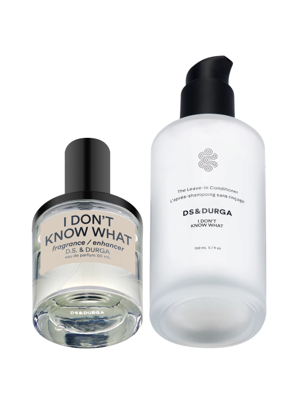 Two DS & DURGA products: a clear glass bottle labeled "I DON'T KNOW WHAT fragrance enhancer" with a black cap, and a frosted pump bottle labeled "The Leave-in Conditioner I DON'T KNOW WHAT.