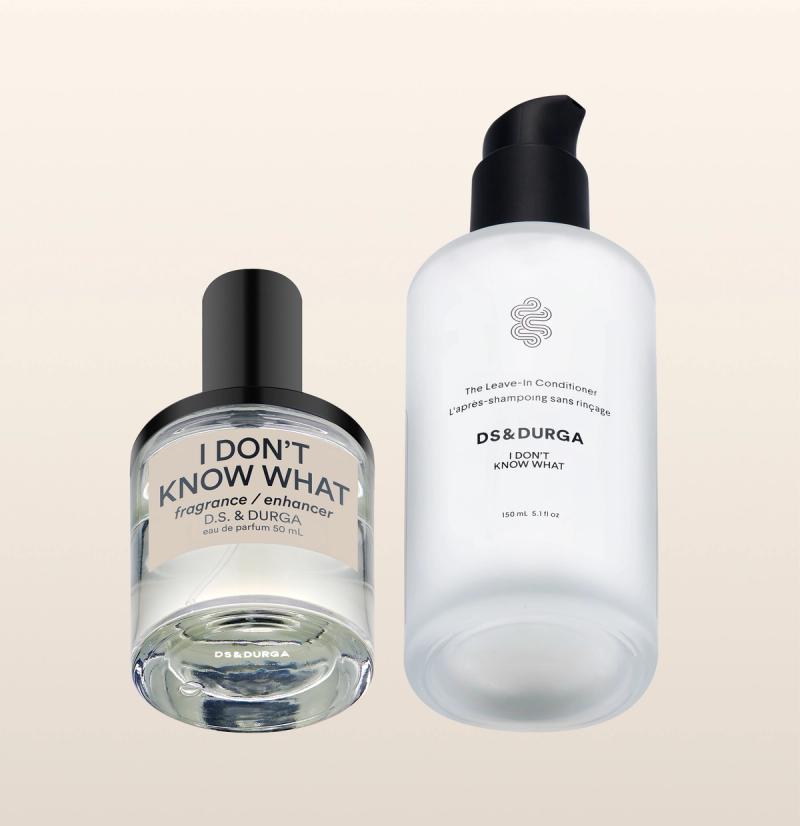 Two DS & DURGA products: a clear glass bottle labeled "I DON'T KNOW WHAT fragrance enhancer" with a black cap, and a frosted pump bottle labeled "The Leave-in Conditioner I DON'T KNOW WHAT.