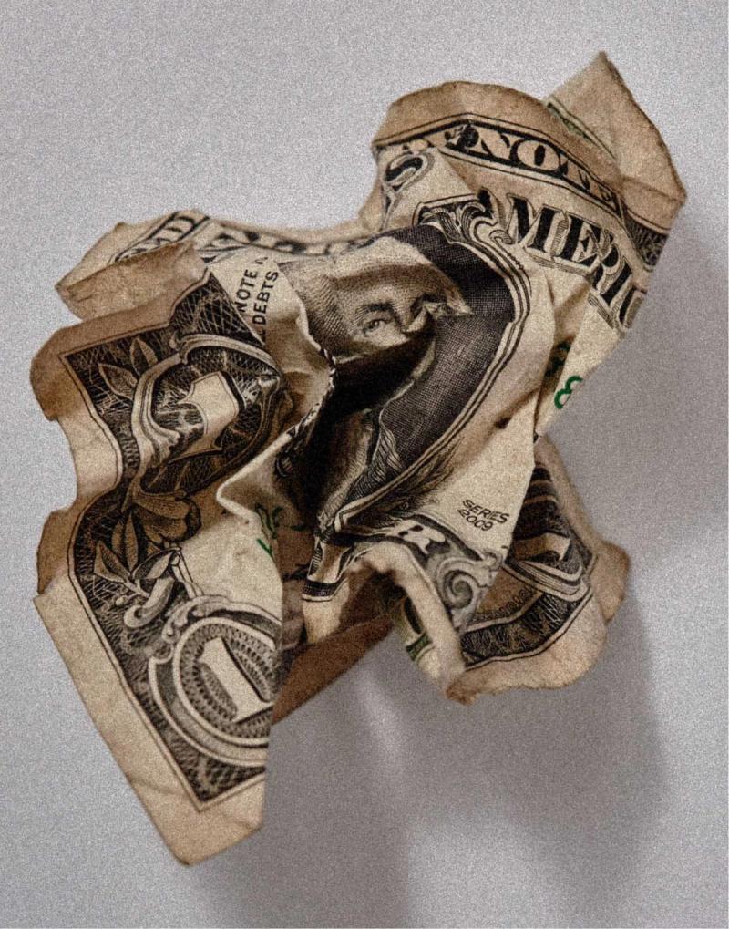 A crumpled one-dollar bill on a neutral background.