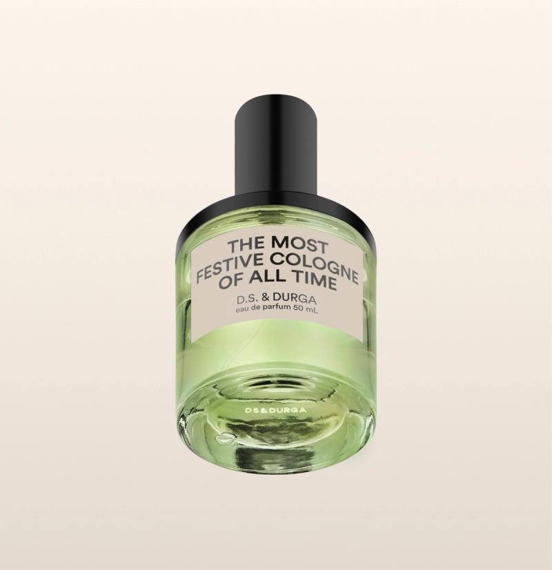 A green-tinted perfume bottle labeled "THE MOST FESTIVE COLOGNE OF ALL TIME" by D.S. & DURGA, eau de parfum 50 mL, with a black cap against a light beige background.