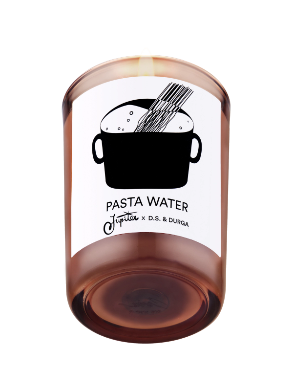 A lit scented candle with label reading "pasta water" by jupiter &amp; d.s. &amp; durga, featuring an illustration of a pot with steam rising, set against a transparent background.