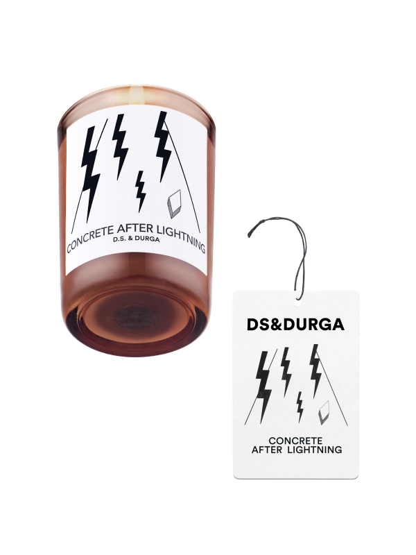 An elegant, lit scented candle by d.s. & durga with concrete after lighting fragrance, accompanied by a matching auto fragrance.