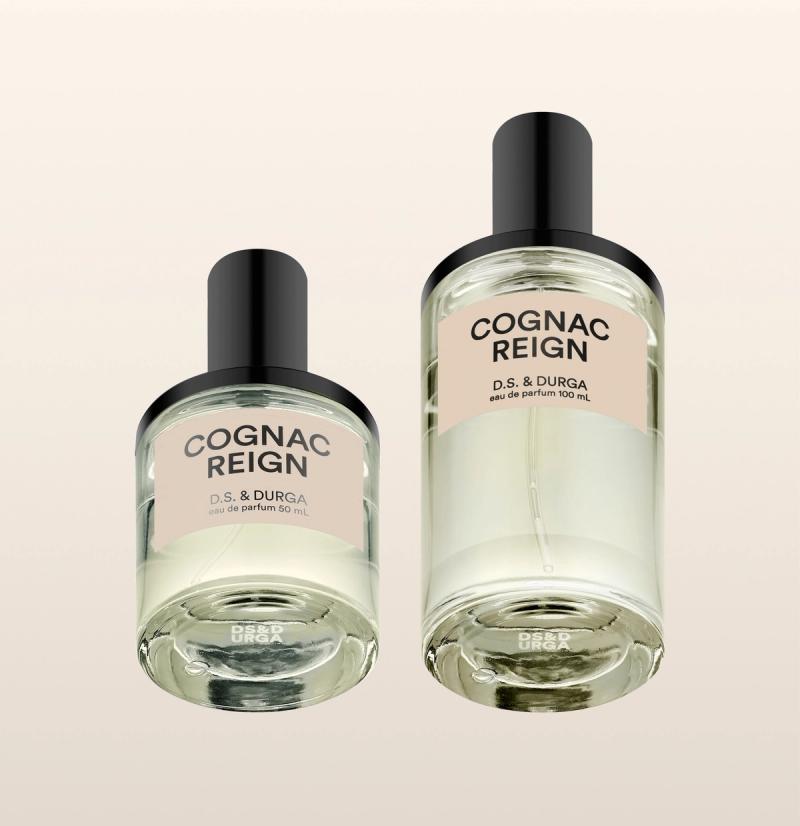 Two clear perfume bottles labeled "COGNAC REIGN D.S. &amp; DURGA" with black caps, shown against a light beige background. The left bottle is smaller (50 mL) and the right bottle is larger (100 mL).