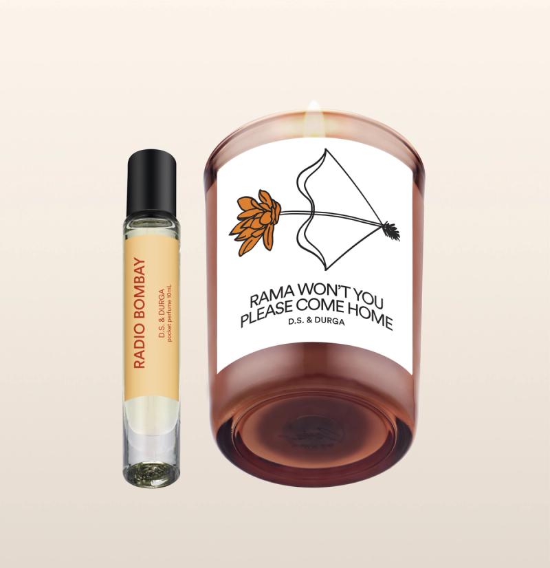 A perfume roller labeled "Radio Bombay" stands next to a lit candle in a glass holder labeled "Rama Won't You Please Come Home" with a bow and flower illustration; both are D.S. & Durga products.