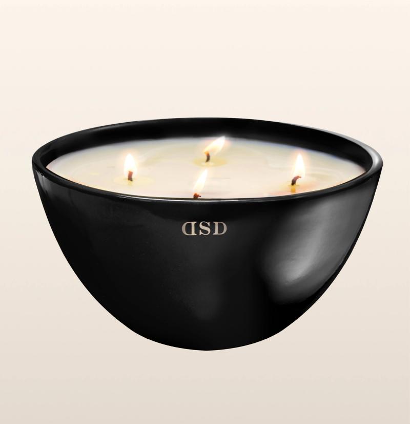  A large, black bowl-shaped candle with four lit wicks, creating a tranquil and aromatic ambiance.