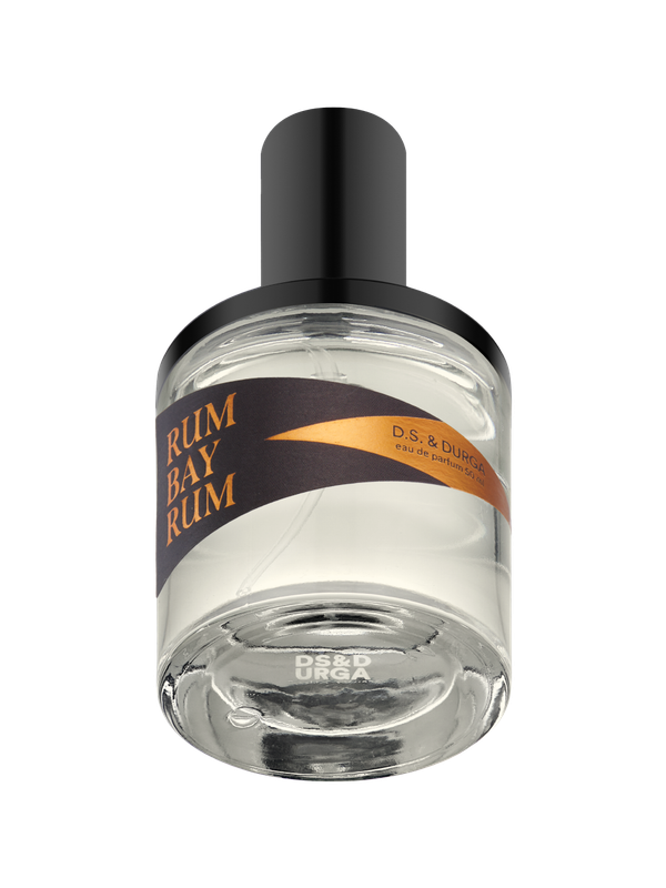A clear glass bottle of D.S. & Durga Rum Bay Rum eau de parfum with a black cap and a dark label featuring gold text and design. The bottle is mostly full and viewed from a slightly low angle.