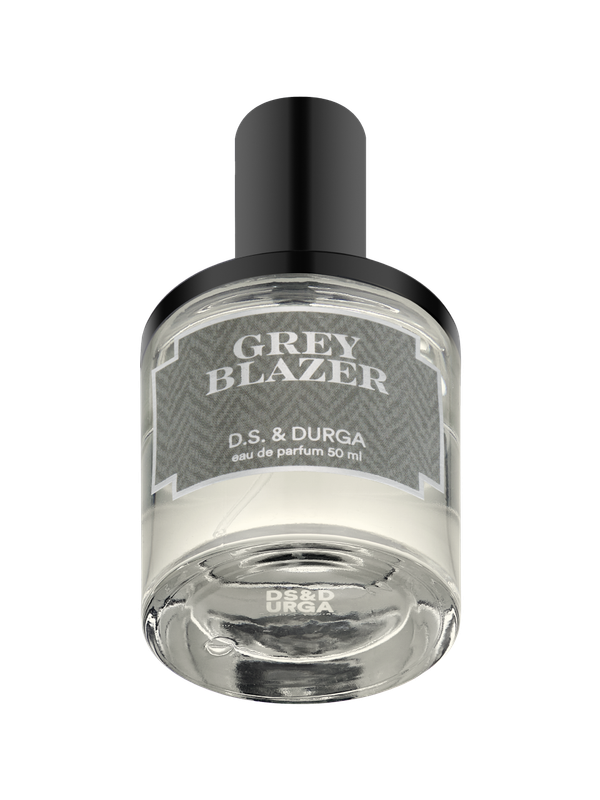 A clear glass bottle of perfume labeled "GREY BLAZER" by D.S. & Durga, eau de parfum 50 ml, with a black cap and gray patterned label.