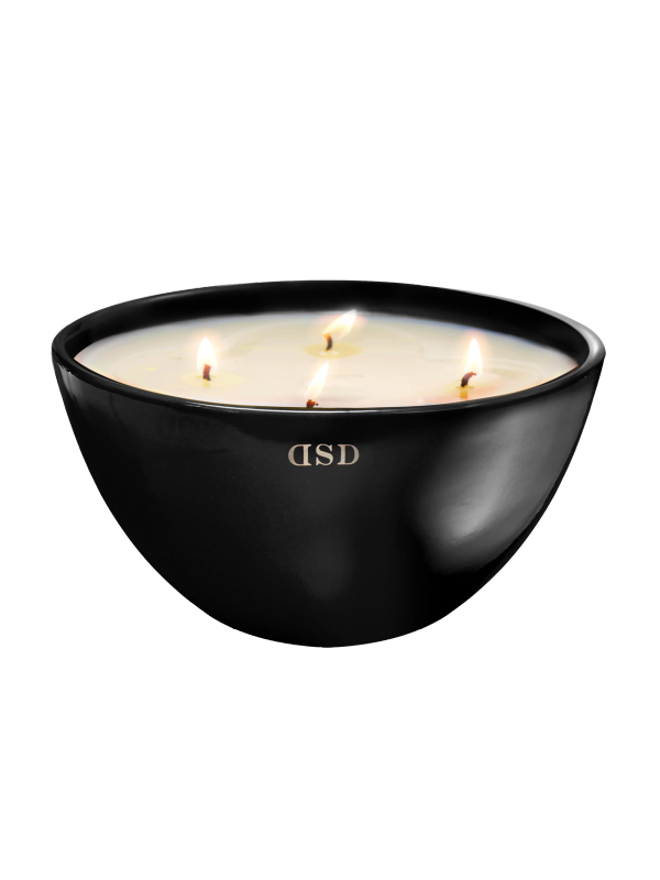 A large, black bowl-shaped candle with four lit wicks, creating a tranquil and aromatic ambiance.