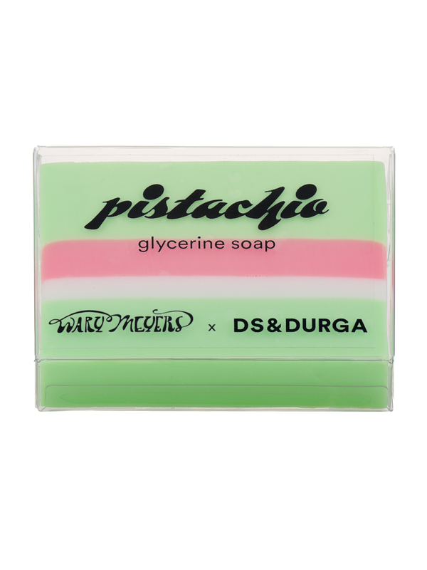 A bar of pistachio glycerine soap in translucent packaging with green and pink layers, featuring a collaboration between brands Wary Meyers and D.S. & Durga.