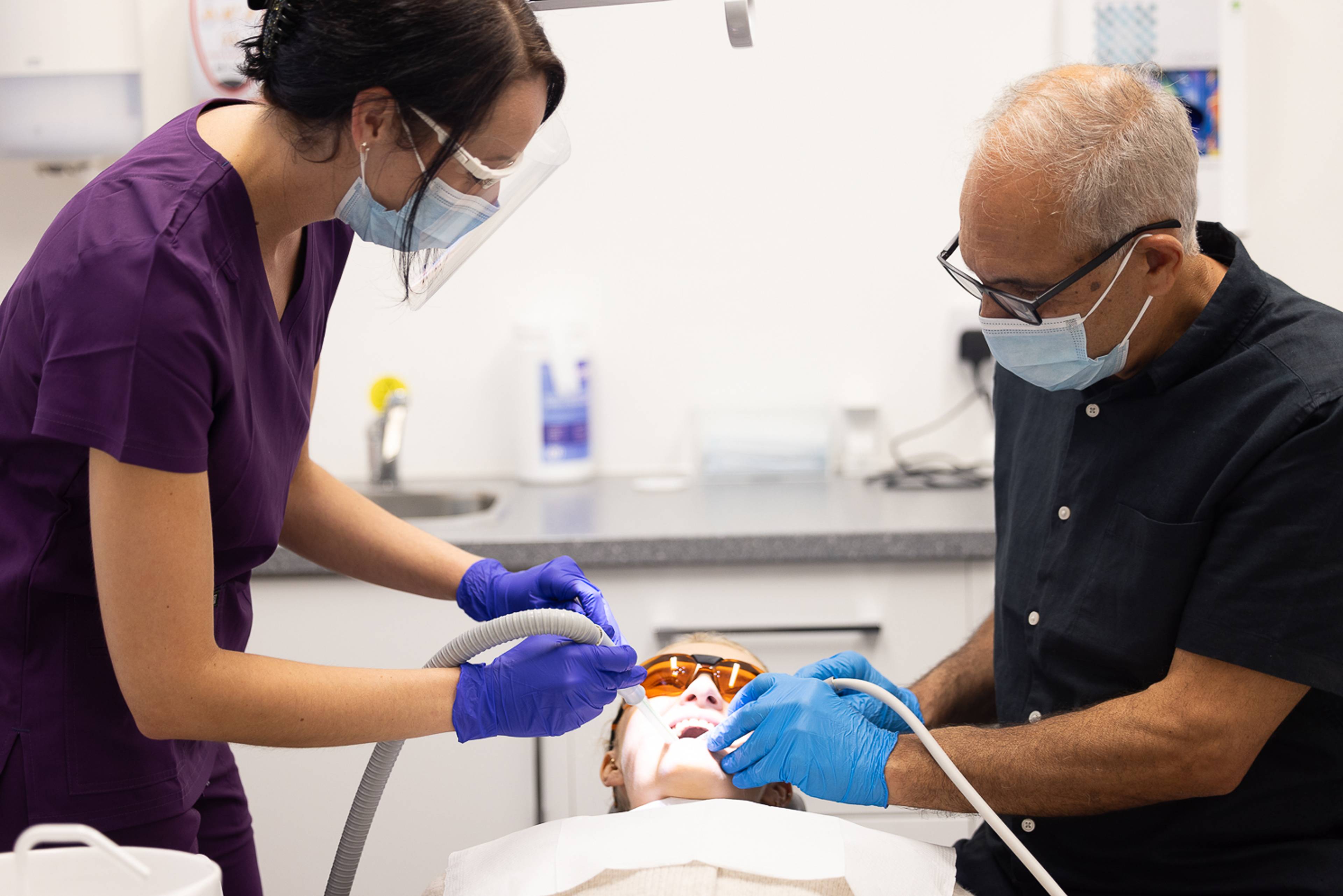 Dentist Shahriar Majlessi and a dental nurse work on a patient who is wearing eye protection