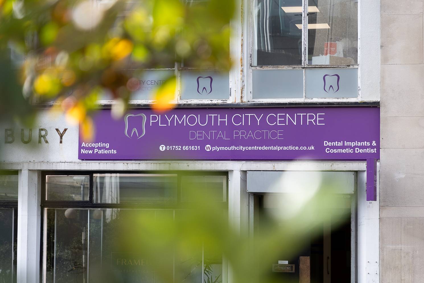 The outside of the clinic slightly obscured by some trees