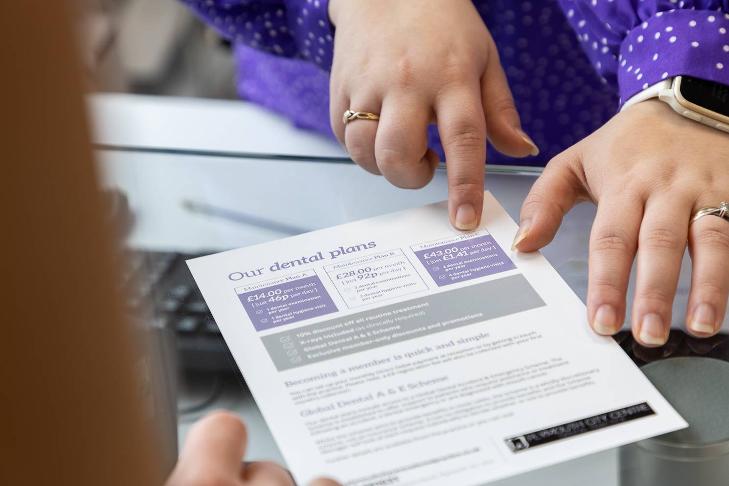 Receptionist Danni Brown shows a patient a leaflet about our dental plans