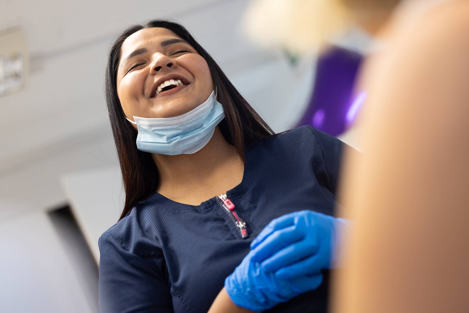 A friendly dental nurse laughing with her face mask pulled down