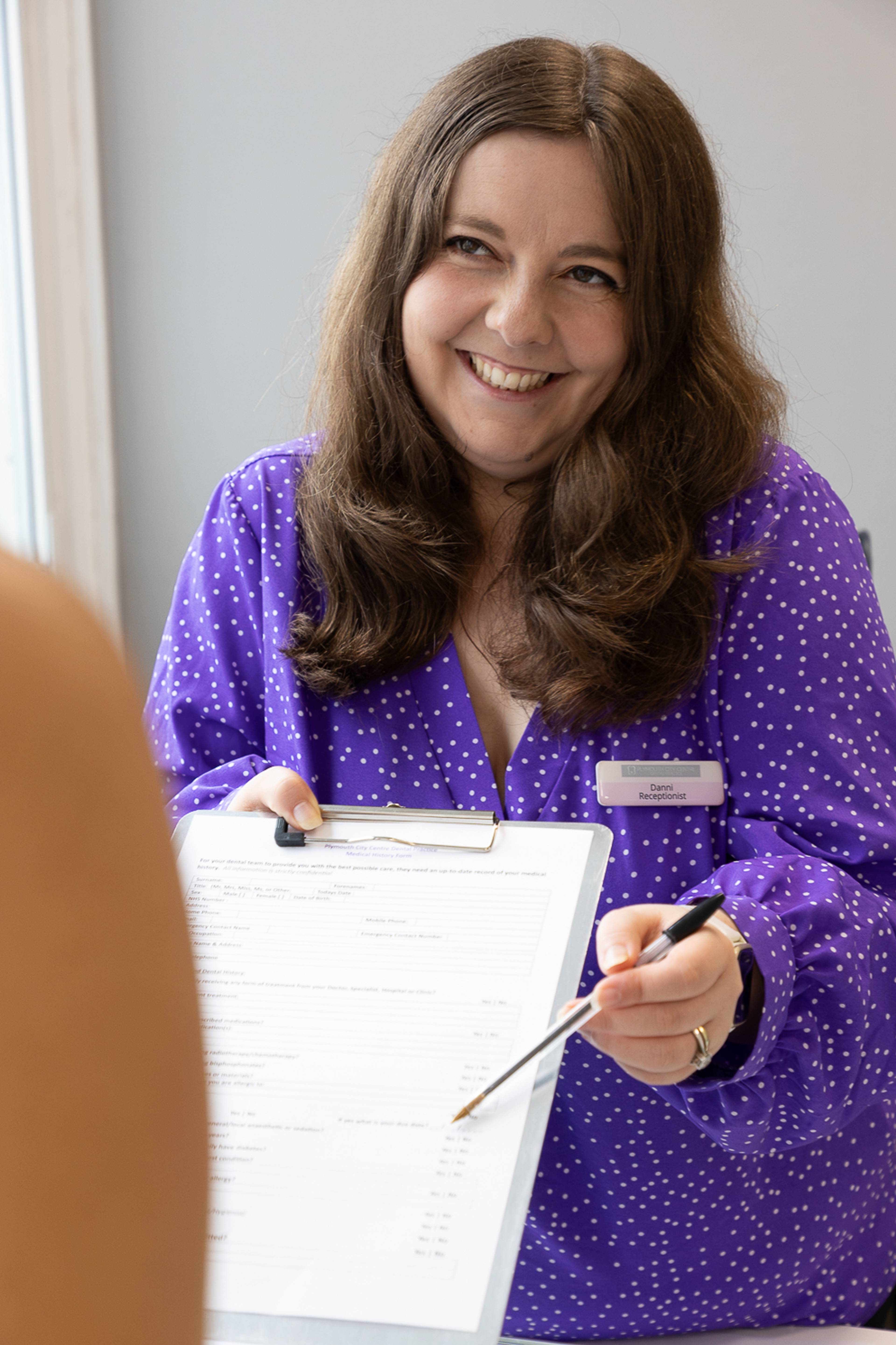 Receptionist Danni Brown hands a sign-up form to a patient