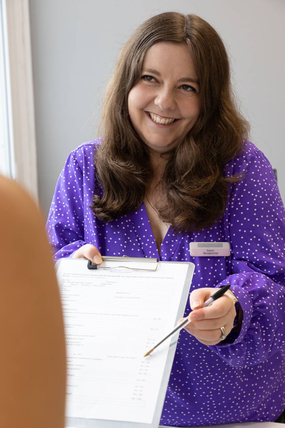 Receptionist Danni Brown hands a sign-up form to a patient
