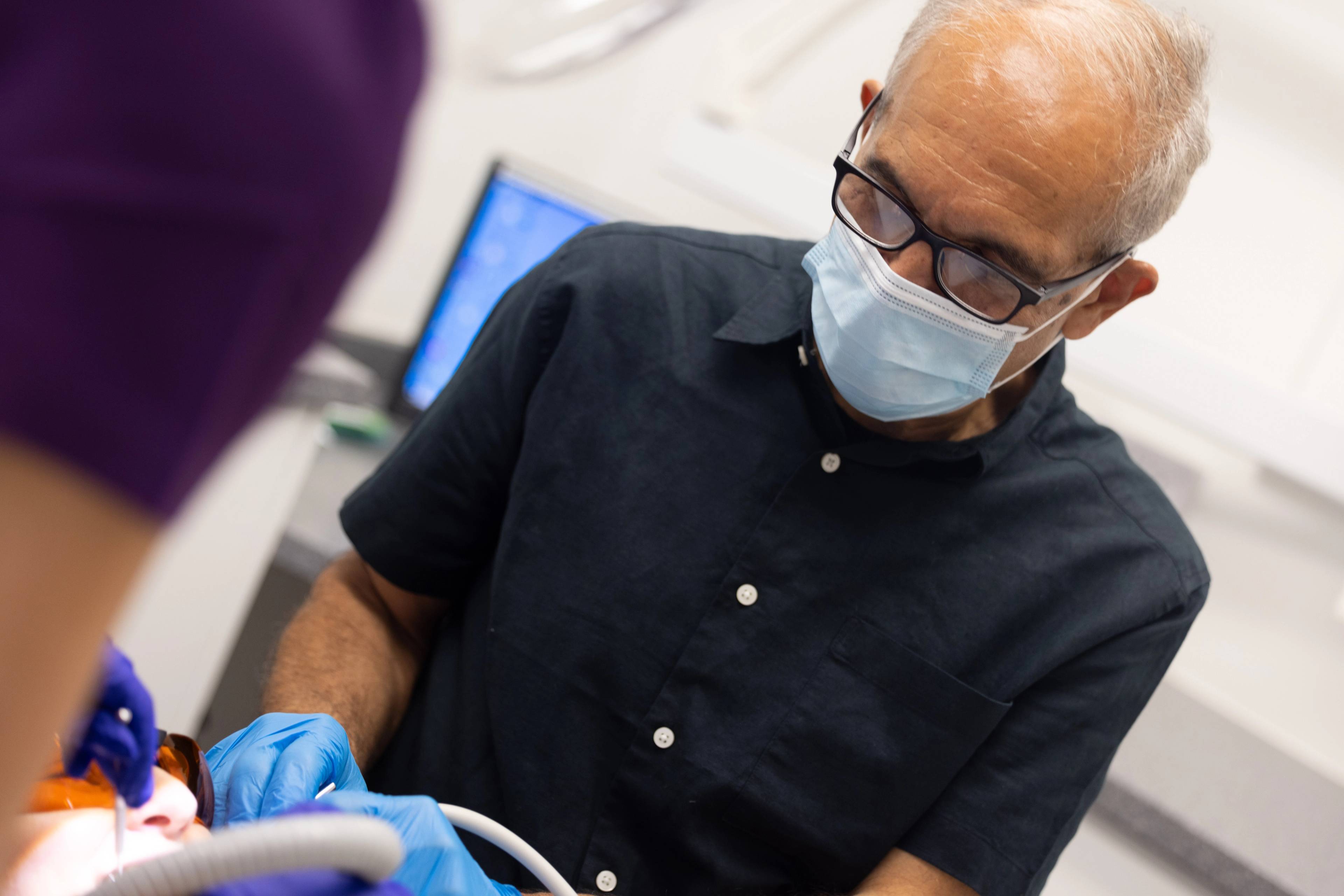 Dentist Shahriar Majlessi giving a general dental exam to a patient who is wearing eye protection