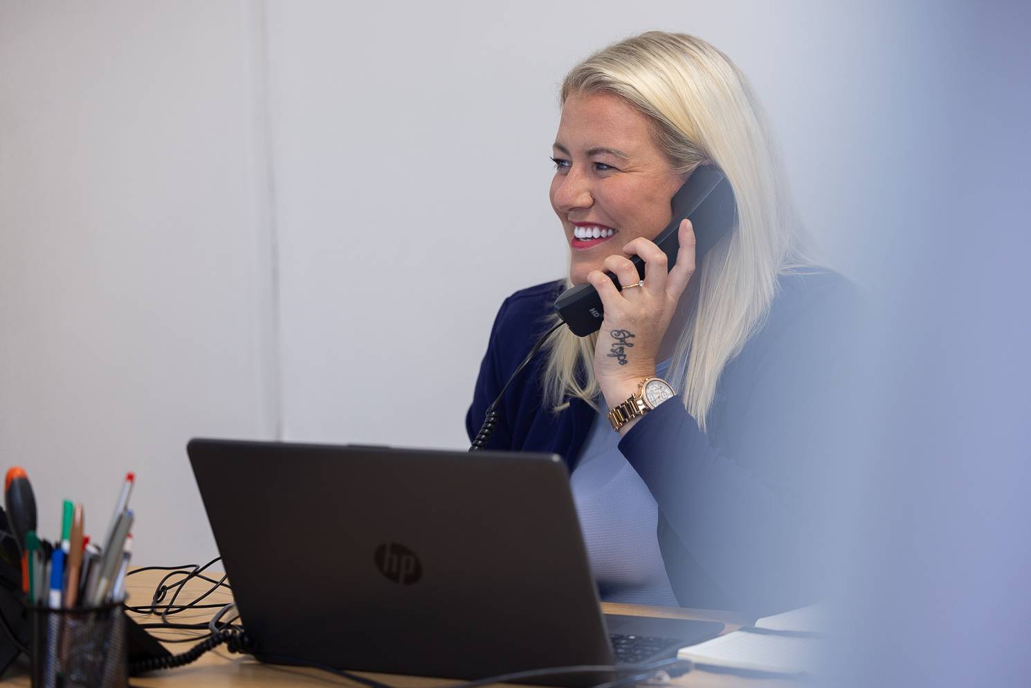 A friendly receptionist smiles while speaking on the phone at Plymouth City Centre Dental Practice