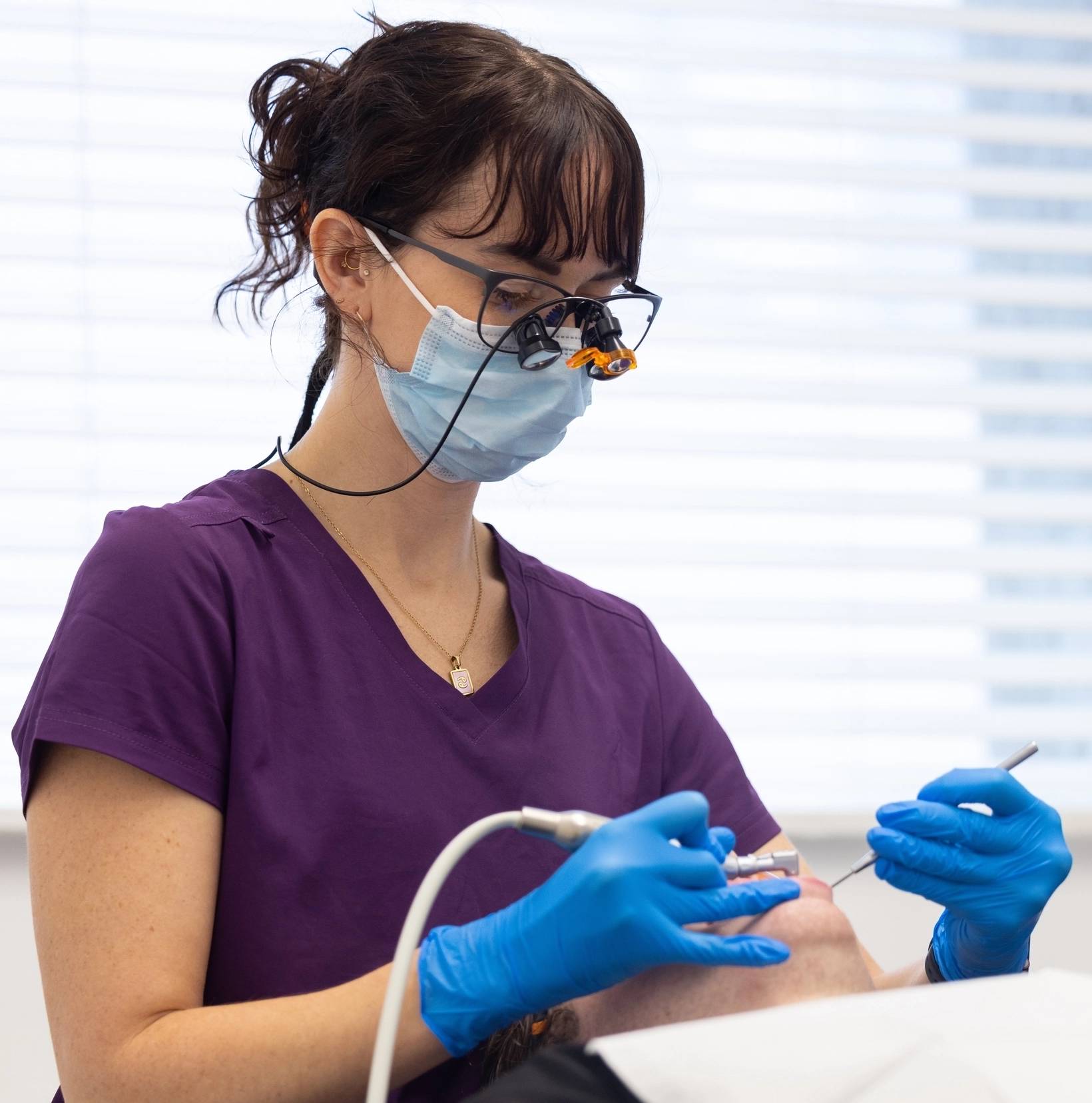 One of our team members examines a patient's teeth while he reclines in a comfortable dental examination chair