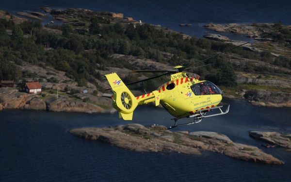Norsk Luftambulanse helikopter over kystlandskap — akuttberedskap i hele Norge