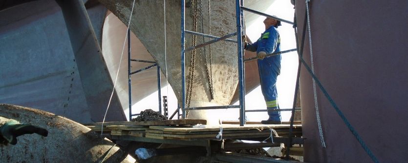A surveyor inspects a propeller in a dry dock