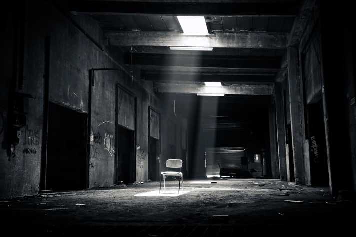 A sinister deserted warehouse with a lone chair