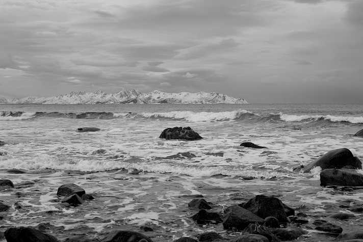 A dramatic, rocky coastline with snow-capped mountains
