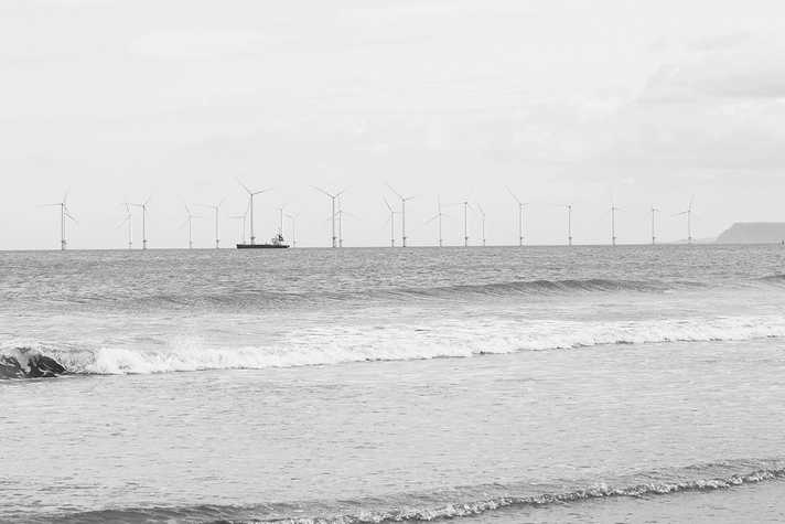 A large vessel steers a course alongside a windfarm
