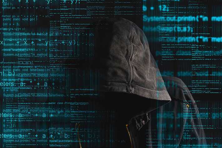 Hooded figure seen surrounded by computer code
